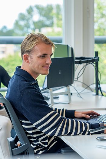 Medewerker werkt geconcentreerd op computer aan feedmarketing in modern kantoor